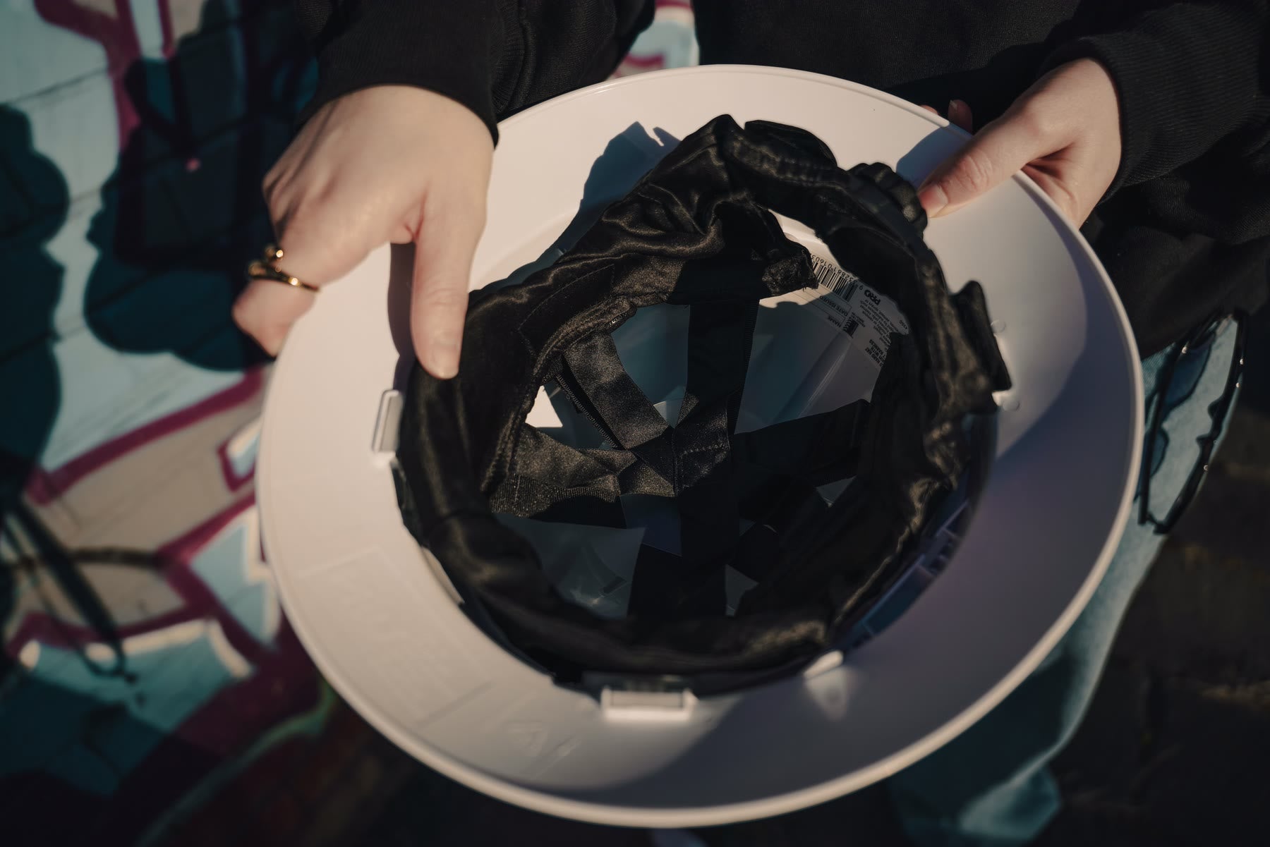 Hands holding a hard hat, showcasing the mulberry-silk Designer Liner inside